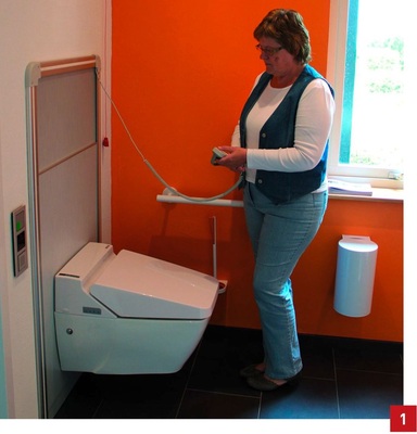 Gegenüber der Waschtischanlage ist das elektrisch höhenverstellbare SFA-Sanimatic-WC mit SaniJet-Dusch-WC angeordnet. Es bietet alle Annehmlichkeiten zur Intimpflege. Das WC ist zwischen 38 cm und 75 cm höhenverstellbar (Oberkante) und mit einer Hebekapazität von 200 kg auch als Aufstehhilfe geeignet. Sinnvoll vervollständigt wird der WC-Bereich durch Griffsysteme und Accessoires der Hewi-Serie 800K.