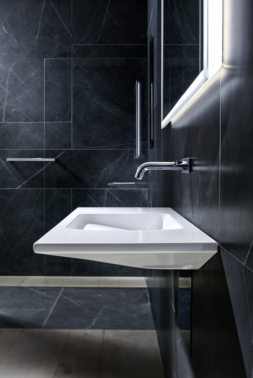 Der Waschplatz steht im Zentrum der Aufmerksamkeit. Die Objekte&nbsp;– Waschtisch, Armatur und Spiegelschrank – halten sich durch die Integration einzelner Elemente in die Vorwand vornehm zurück und eröffnen damit Freiräume bei der Badnutzung.