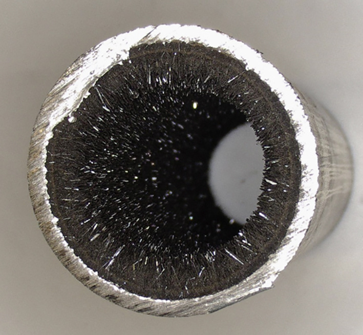Bild 3: C-Stahlrohr mit einem kristallinen Belag aus Magnetit und Kalziumkarbonat (Aragonit), verursacht durch eine relativ hohe Resthärte in Verbindung mit übermäßigem Sauerstoffeintrag.