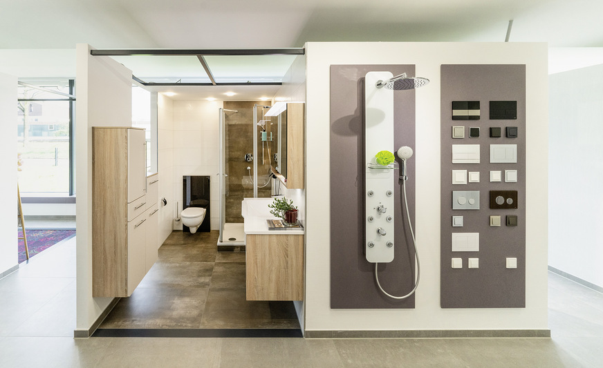 Praktische, helle und optisch passende Stauraummöglichkeiten veranschaulicht die Badlösung in Cube 3. Bei der Dusche wurde bewusst auf eine Wanne mit Sockel gesetzt, wie sie nach wie vor bei vielen Renovierungen eingebaut wird. Die geschlossenen Außenwände des Cubes wurden hier mit zwei praktischen Wanddisplays bestückt. Das Display rechts zeigt, wie sich WC-Betätigungsplatte sowie Lichtschalter (und Steckdosen etc.) optisch perfekt aufeinander abstimmen lassen.