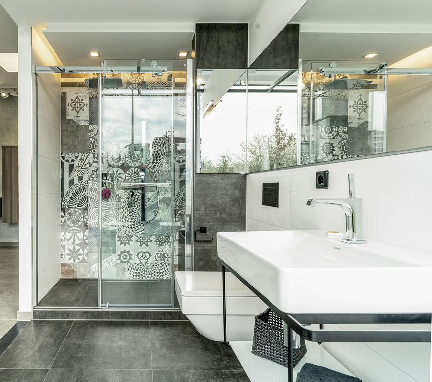 Der zweite Bereich von Cube 3 veranschaulicht eine weitere typische Renovierungslösung: In den Bereich, wo früher die alte Badewanne stand, wird eine großzügige Duschlösung mit Glasschiebetür und (optionalem) Sitzplatz hinter einer gemauerten Wand eingebaut. Weitere Besonderheit: ein durchgehender Spiegel über Waschbecken und Wand-WC, der sich an der schmalen Seitenwand des Duschbereichs fortsetzt. Er vergrößert den Raum optisch.