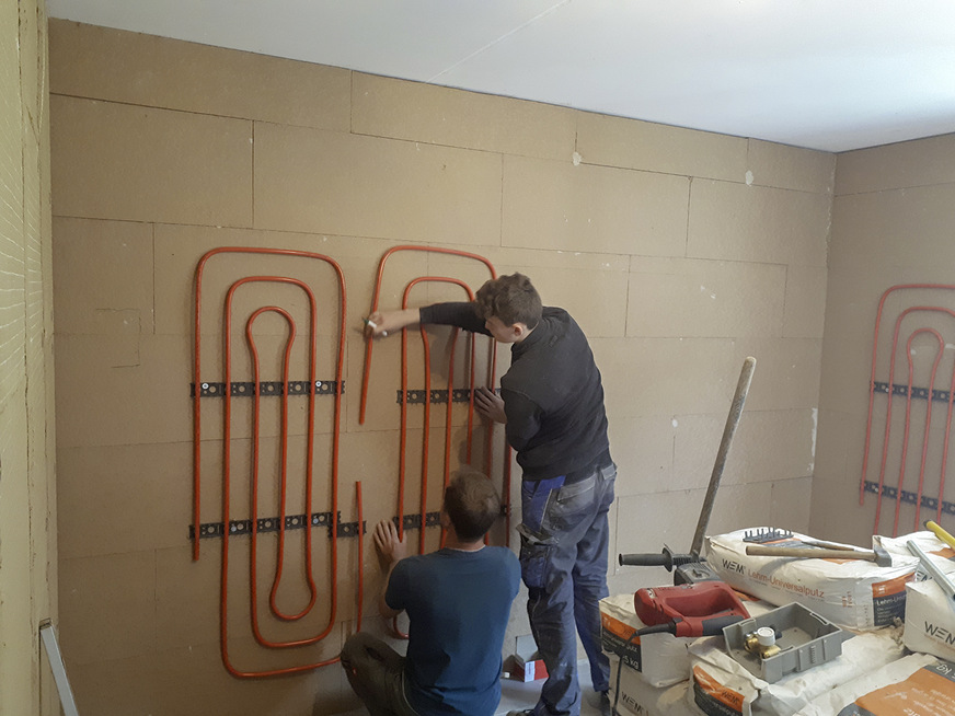 Montage einer Wandheizung auf Innendämmung an einer Kellerwand bei der Herstellung eines Arbeitszimmers.