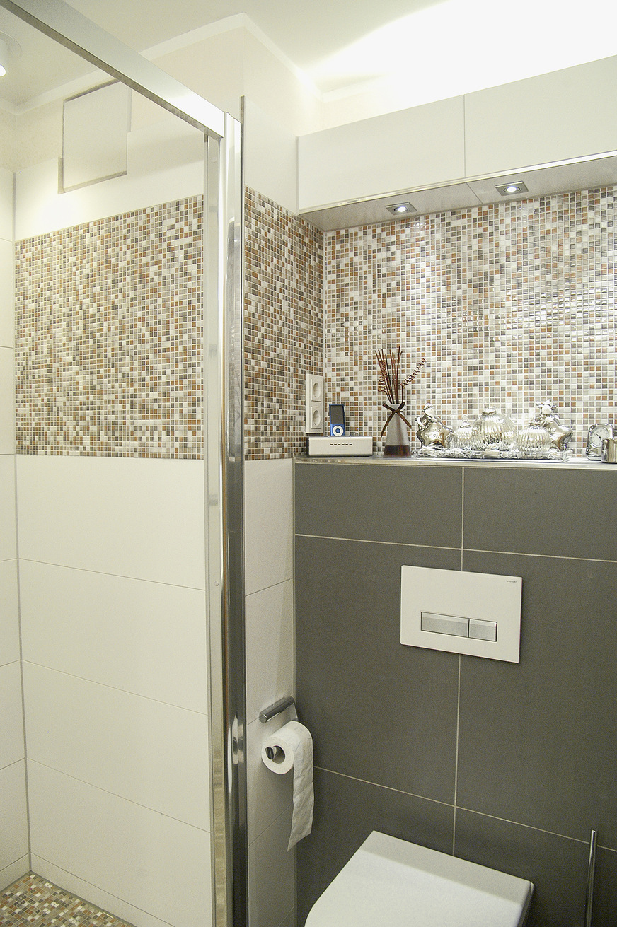 Mit breiten Mosaikstreifen können Verbindungen geschaffen und „Ecken“ harmonisiert werden. Der Duschboden findet sich in der Wandgestaltung wieder.