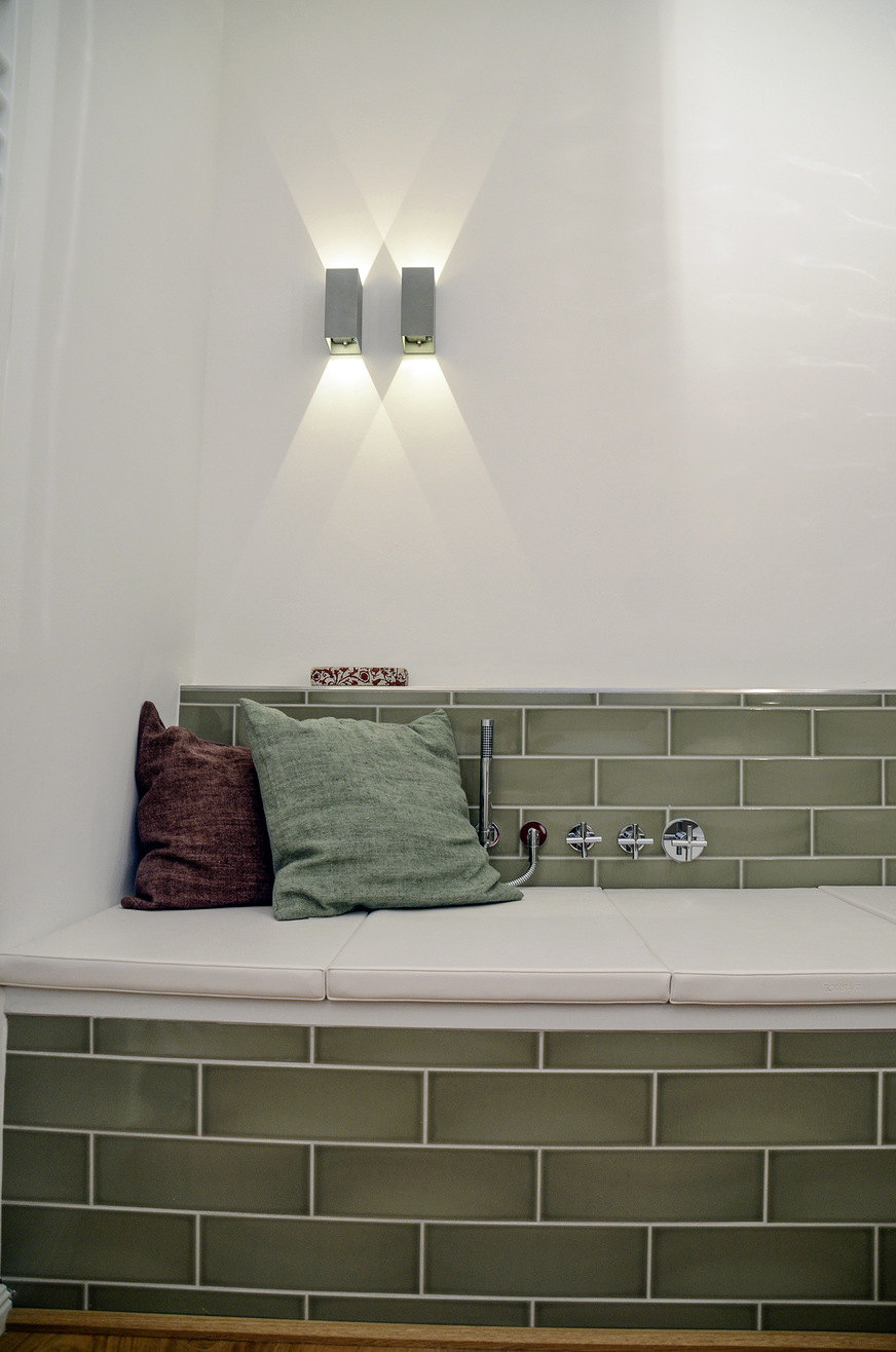Ein Wandleuchten-Pärchen über der Badewanne sorgt für ein gemütliches Erholungsszenario. Die Reflexion auf der Wand ist bestimmend für den schönen Blick.