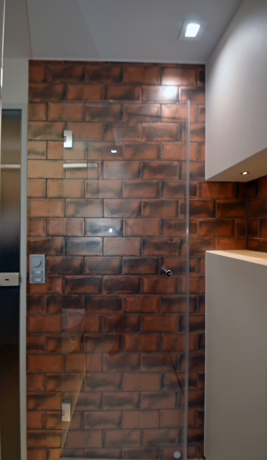 Die dritte Duschwand fällt mit Fliesen im Metrolook ins Auge. Die angrenzende Nische wird eingebunden, indem das Material auch an der Rückwand weiter geführt wird. Kontraste durch Groß und Klein und durch Hell und Dunkel.