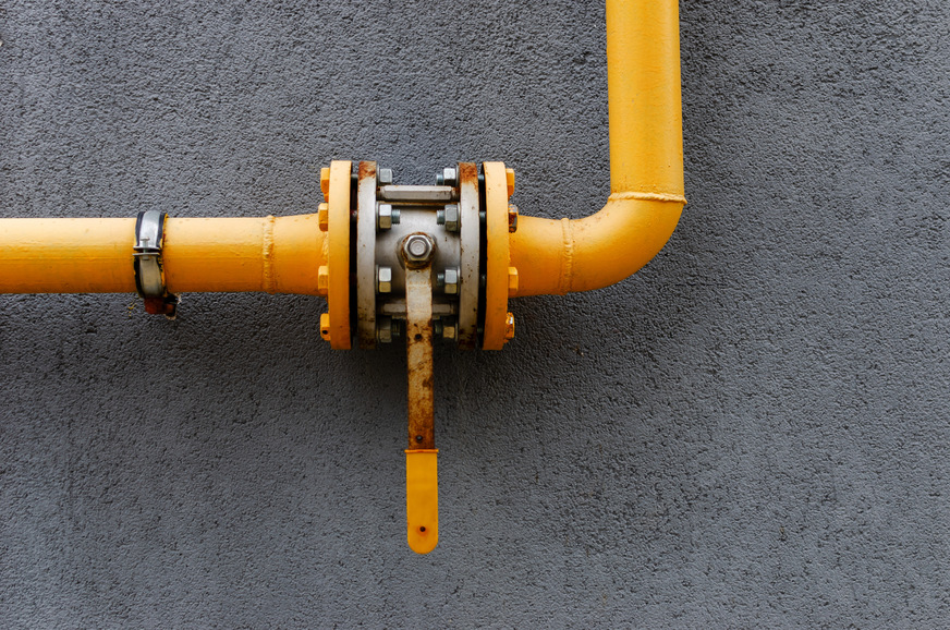 yellow gas pipe with a crane goes along the facade of a new multi-storey building. House connected to gas for domestic use