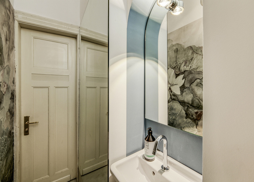 Der neue Spiegel über dem Waschbecken ist an die Form der Nische angepasst. Die Lampe für die Spiegelbeleuchtung – natürlich ebenfalls rund – ist aus Platzmangel auf dem Glas montiert.