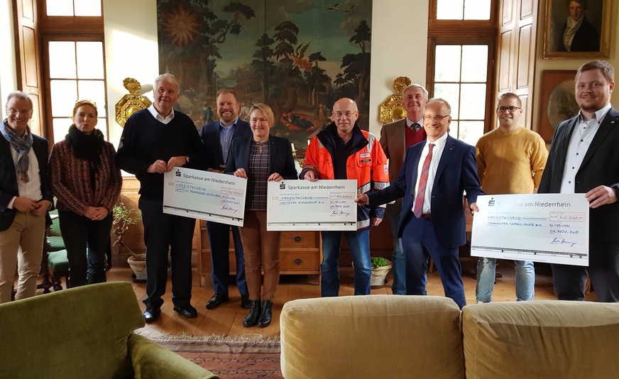 Die Spenden wurden von Christine Roßkothen, Vorstand der Heinz Trox-Stiftung (5. v. l.) und Thomas Mosbacher, Geschäftsführer der Trox GmbH (3. v. r.) an Michael Freiherr Spies von Büllesheim, Bürgermeister der Gemeinde Metternich (4. v. r.), Dr. Cornelia Lawrenz, Geschäftsführerin der Stiftung Technisches Hilfswerk und Albrecht Broemme, Ehrenpräsident und Mitglied des Vorstands der Stiftung Technisches Hilfswerk (2. und 3. v. l.), Ingo Radtke, Leiter der Fluthilfe des Malteser Hilfsdienstes (5. v. r.) und Julian Felix Müller, Mitglied des Regionalvorstands der Johanniter-Unfall-Hilfe (1. v. r.) übergeben. Mit dabei waren weitere Vertreter der Hilfsorganisationen, ein Vertreter der Freiwilligen Feuerwehr Metternich sowie Einwohner.