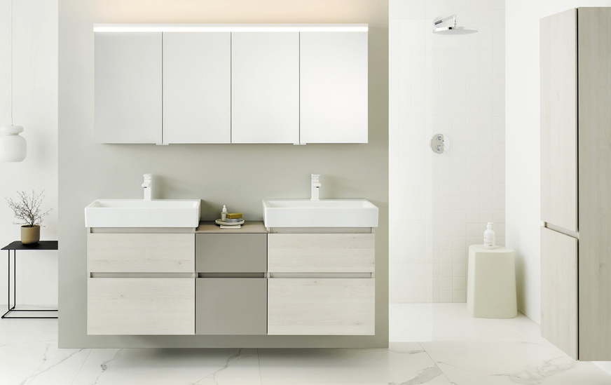 Schlankes Doppel für schicke Schlauchbäder: Die neue Kollektion „Lin20“ von Burgbad bietet tiefenreduzierte, alltagstaugliche Waschtische und Schränke in minimalistischem Design – hier im Materialmix von Eiche Dekor Merino und Basaltgrau matt. Das neue Beleuchtungskonzept des Spiegelschranks bietet eine indirekte Deckenbeleuchtung.