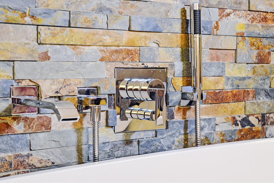 Die quadratischen Grundformen der Armaturenteile sind nicht nur Wunsch der Bauherrin, sondern auch eine Voraussetzung für die Montage. Die starke 3­D-­Optik der Wandgestaltung macht es notwendig, die Schiefersteine in Form der Armaturenblenden auszuklinken.