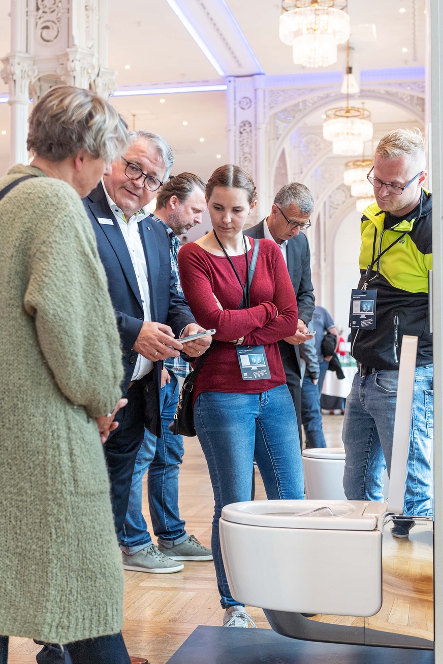 Besucher des Geberit Bau-Treffs nehmen das Dusch-WC Geberit AquaClean Mera unter die Lupe.