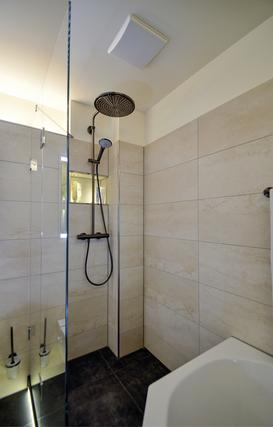 Die verflieste Duschzone – die sich bis zum Wannenkasten ­erstreckt – ist über eine kleine Stufe zu erreichen, versehen mit einem LED-Band mit Nachtlichtfunktion ist sie nützlich und schön anzusehen zugleich.
