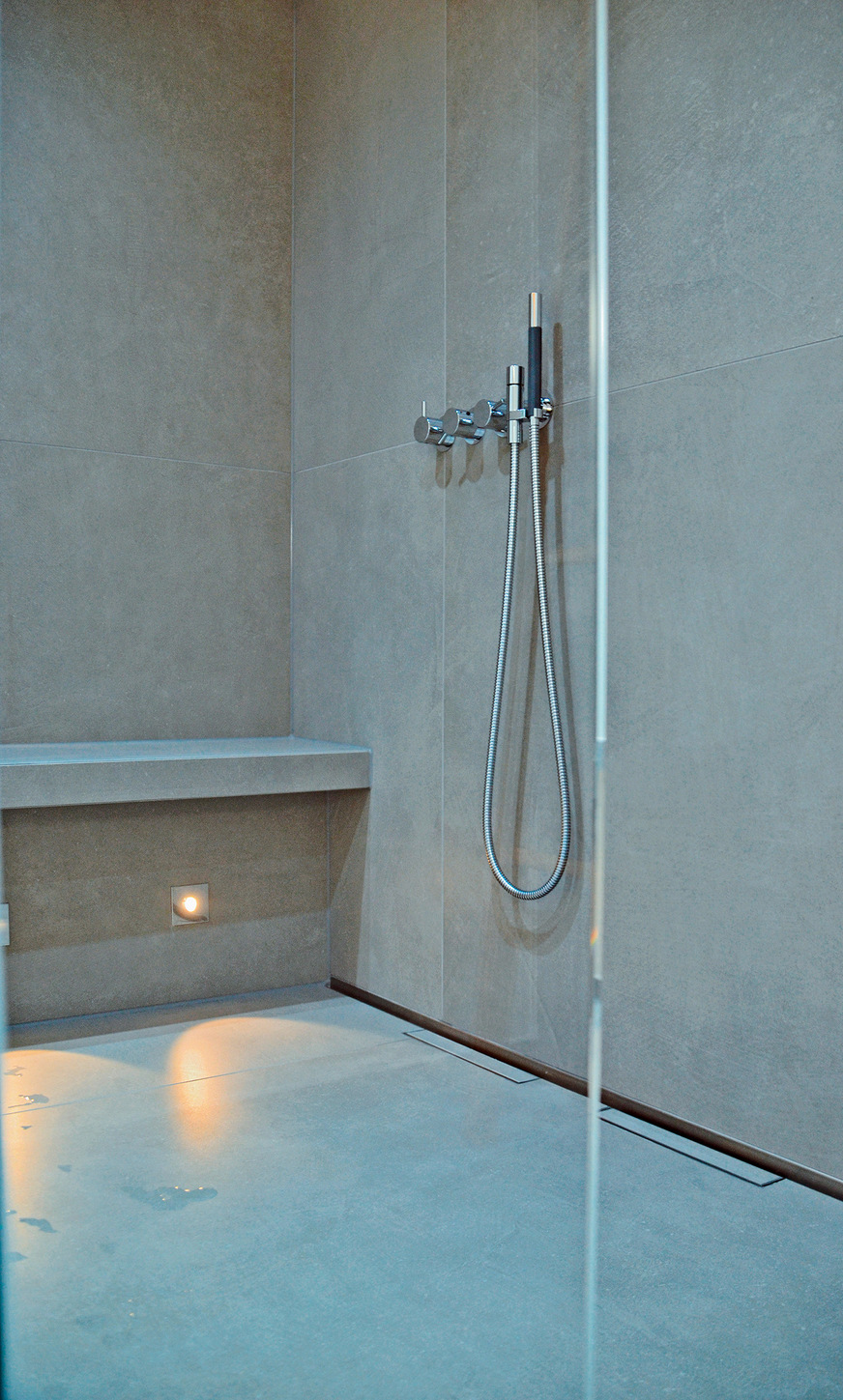 Die großformatigen Fliesen im Format 120 × 120 cm sind im Fugenschnitt auch an der Wand im Duschbereich verlegt