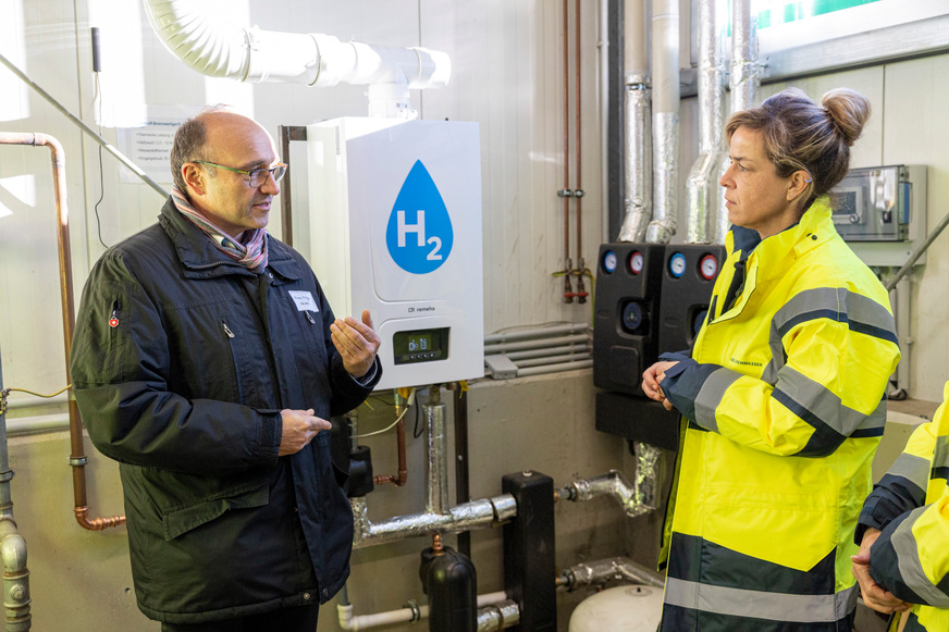 Remeha-Vertriebsleiter Franz Killinger und NRW-Wirtschaftsministerin Mona Neubaur im Gespräch vor dem 100 %-Wasserstoff-Brennwertkessel von Remeha.