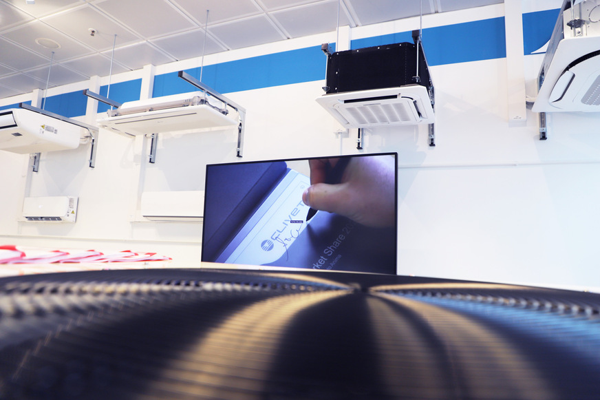 Einblick in den Schulungsraum mit Präsentationsbildschirm und Wand-Klimageräten. Zu sehen sind Cristallo Single-/Multi-Split, GWMN VRF sowie die Deckengeräte Ceiling&Floor, 1-Wege-Deckenkassette und 4-Wege-Deckenkassetten.