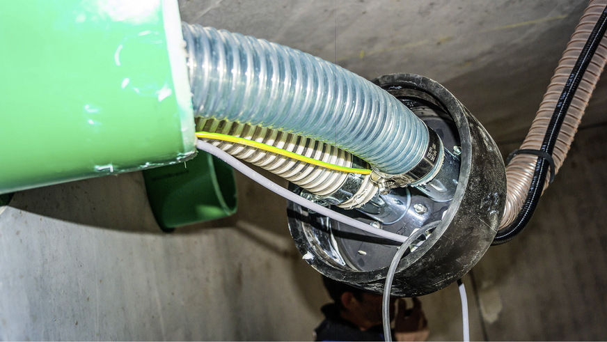 Schnittstelle Adapterplatte im Pellet­speicher: Saugschlauch (weiß) als ­flexible Kunststoffleitung, daneben Rückluftschlauch (blau). Von hier bis zur Saug­turbine am Heizkessel ist der ­Heizungsfachbetrieb für das Verlegen der Schläuche verantwortlich.