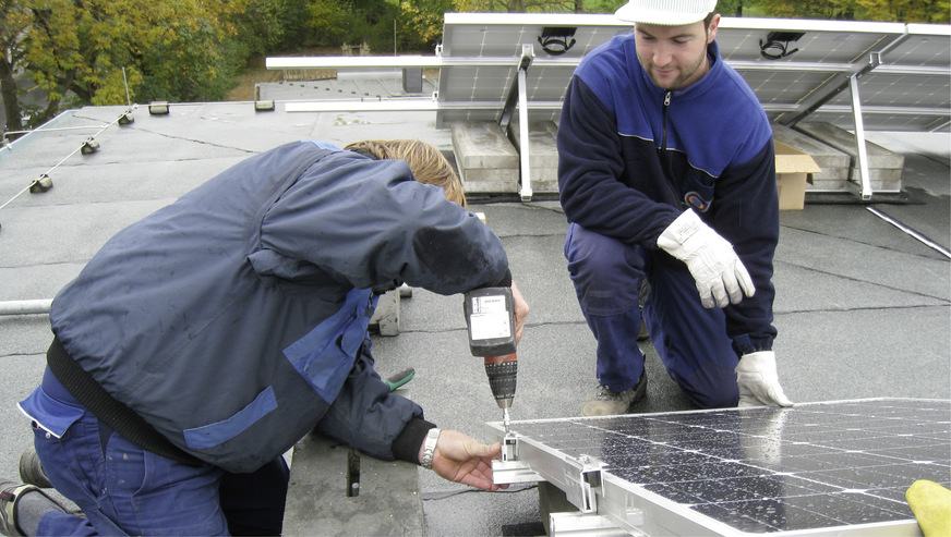 Der Meister zeigt dem Auszubildenden, wie die Arbeiten an einer Photovoltaikanlage in der Praxis durchgeführt werden.