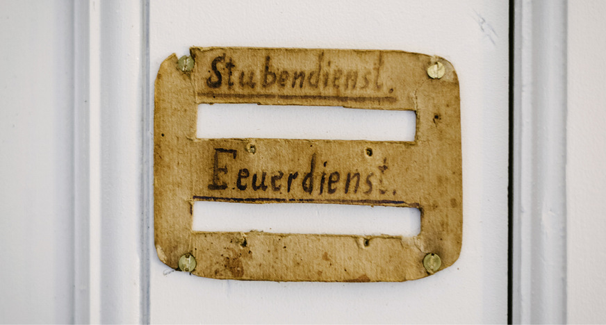Das wieder angebrachte Bediensteten-Schild ist ein Hinweis auf die frühere Nutzung, eine Reminiszenz an die im Gebäude unsichtbar enthaltenen individuellen Geschichten.