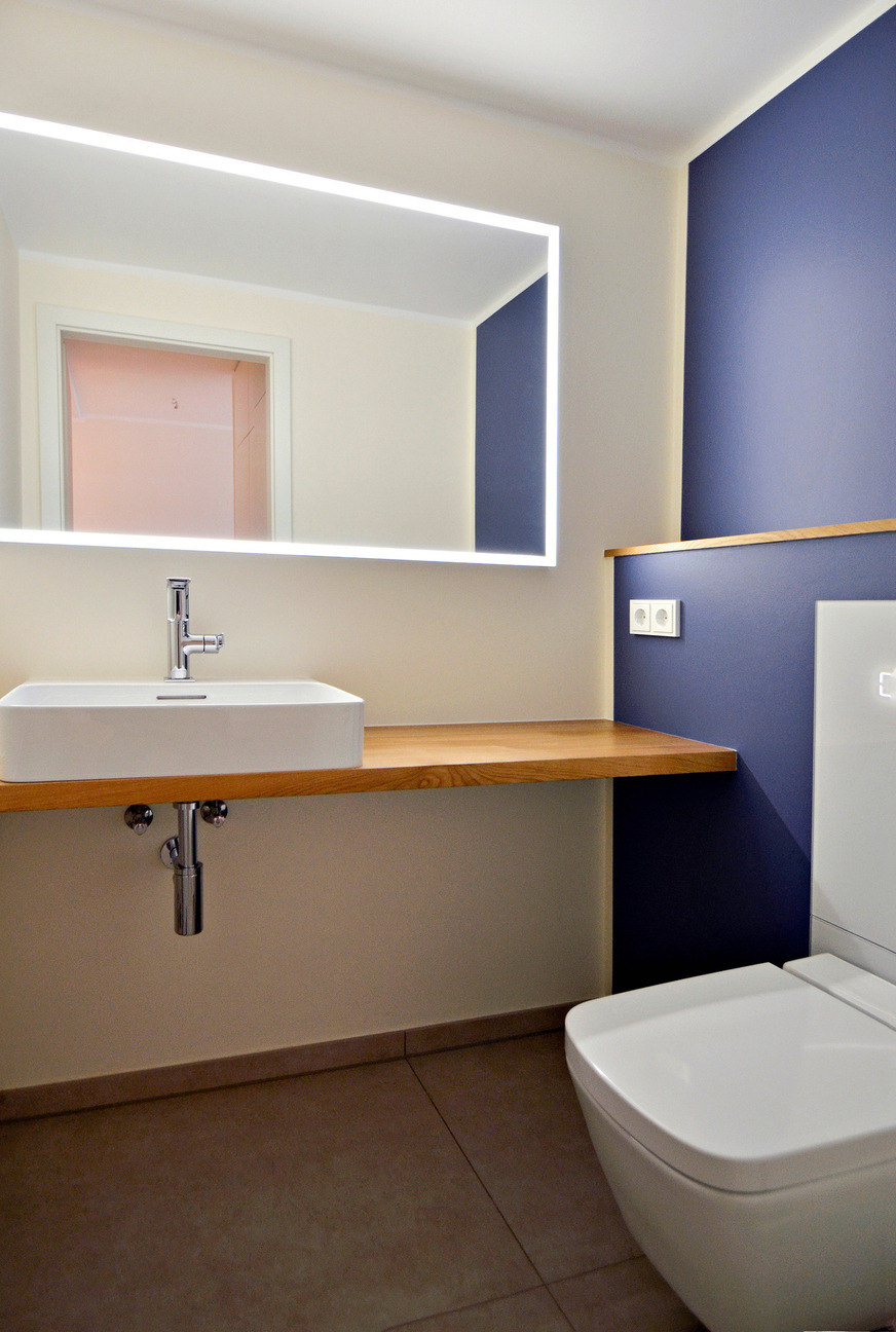 Ein überbreiter ­Spiegel mit Rundumbeleuchtung übernimmt im Gäste-WC die Lichtfunktion.