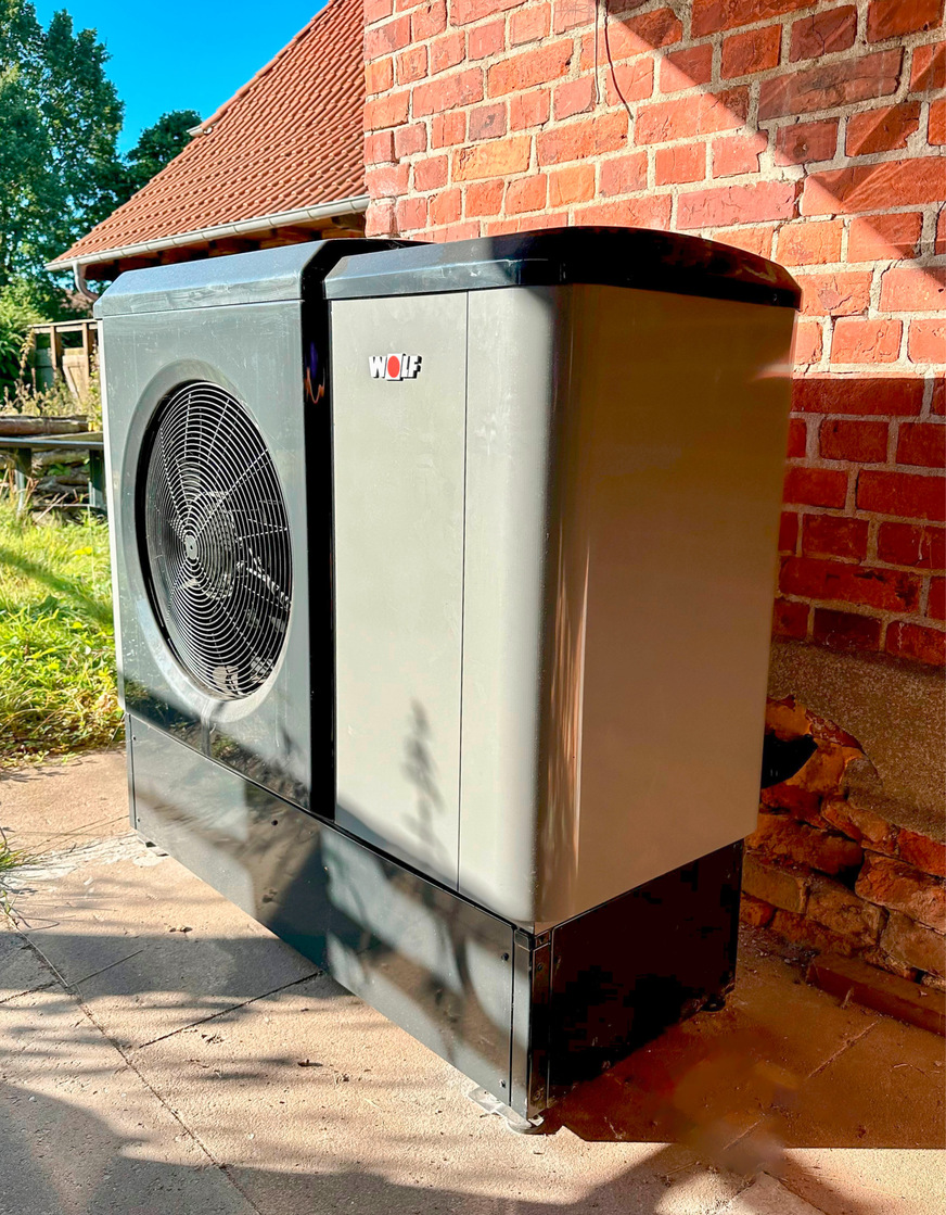 Die neue Wärmepumpe befindet sich im offenen Schuppen an der Rückseite des Altbaus.