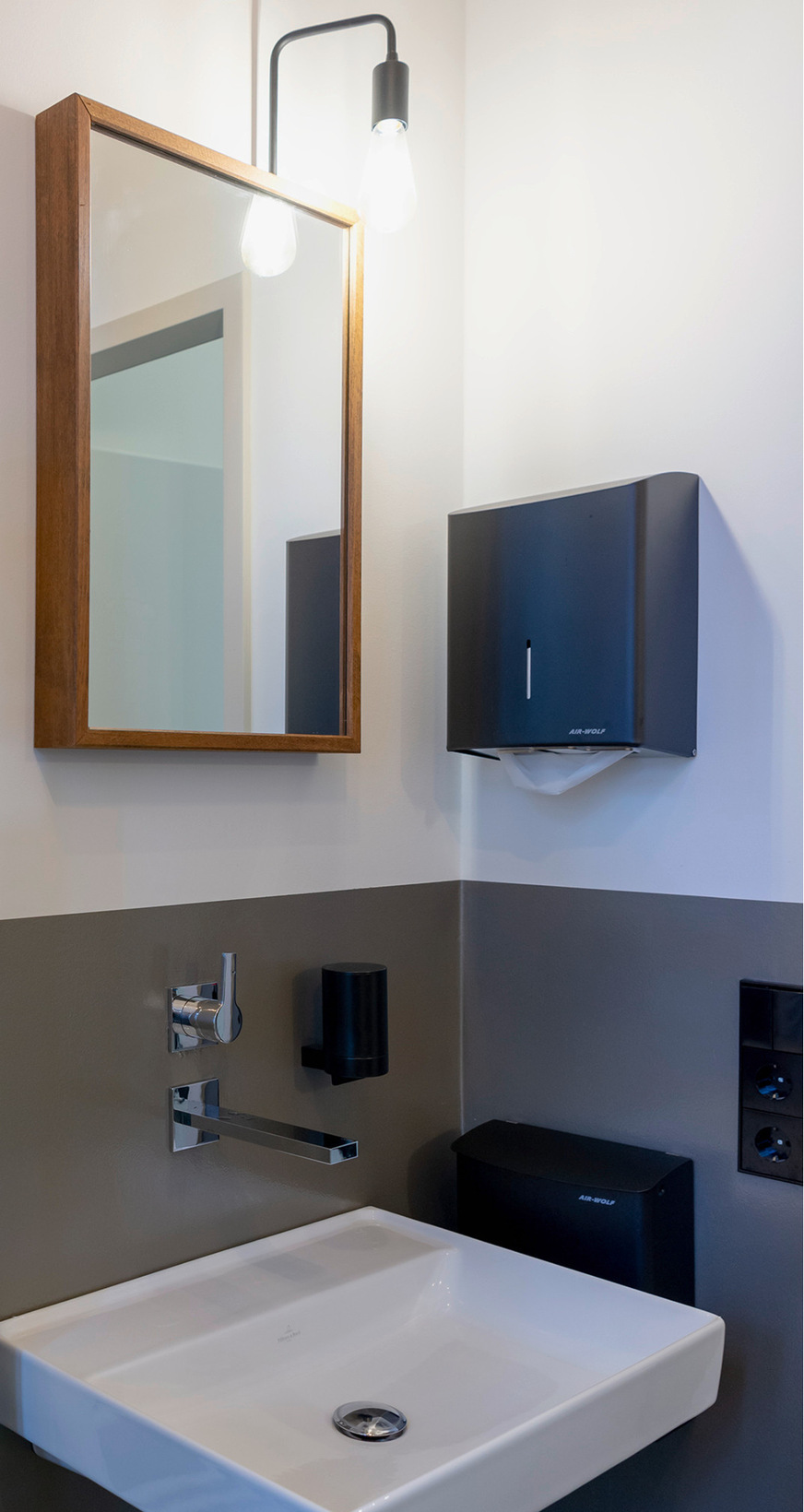 In den eigenen Räumen hat das Planungsbüro „­raumdeuter“ eine Werkstattatmosphäre realisiert: Wände blieben unbehandelt, die Akustik wird mit Holzwolleplatten perfektioniert und Elektroinstallationen sind sichtbar und kontrastreich in&nbsp;Schwarz montiert. Auch hier zieht sich das Konzept bis in das WC. Neben einer Dusche bietet der Raum genügend ­Bewegungsfläche für Menschen im Rollstuhl – ­Haltegriffe können nachgerüstet werden, der Waschtisch ist bereits ­unterfahrbar. Vielleicht noch selten, aber von Weltoffenheit und der Akzeptanz bestimmter ­Nutzeranforderungen ­zeugen bei einem Unternehmen ­zusätzlich alternative WC-Formen, etwa Hock-Lösungen bei einer besonders inter­national geprägten Belegschaft.