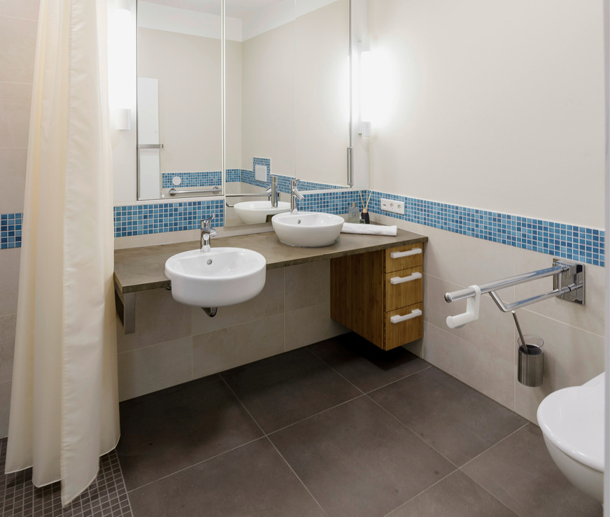 In der barrierefreien Musterwohnung in der Sredzkistraße in Berlin, einem Projekt der „SelbstBau ­Mietergenossenschaft e.G.“, beinhaltet das Gesamtgestaltungskonzept auch einen umlaufenden ­Kontraststreifen. Dieser unterstützt Menschen mit Sehbeeinträchtigungen bei der Orientierung. In den Bädern ­wurde das Element mit farbig passenden Mosaikfliesen umgesetzt.