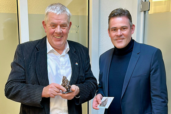 Landesinnungsmeister Ulrich Grommes ehrt Norbert Borgmann (li.) mit einer Bronzeskulptur, die die drei Elemente Feuer, Wasser und Luft künstlerisch miteinander verbindet.