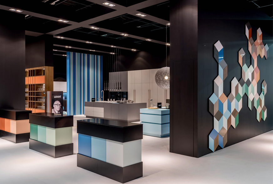 Selbst Ausstellungen von hochwertigen Küchen- und Badherstellern müssen nicht immer puristisch sein, und Langeweile ist nicht gerade geschäftsbelebend. Farbe schafft Abhilfe, wie analog ausgewählte Nuancen und lebhaftes Wandmosaik bei Leicht Küchen zeigen.