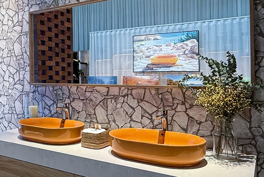 Sommersonnengelbe Aufsatzwaschtische flankiert vom Mimosenstrauß. Großzügige Inszenierung mit leicht rustikalem Fliesenmosaik, nicht nur fürs Landhaus passend (gesehen bei Toto).