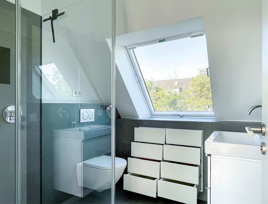 Die Vorwand unter dem Fenster wurde bis zur Höhe der Fensterbank vorgezogen und bietet viel Ablagefläche. Ein Einbauschrank auf Maß vom Schreiner nutzt die Tiefe optimal aus.