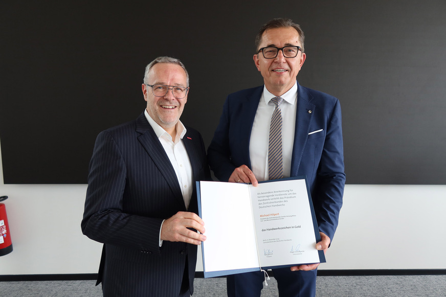 Jörg Dittrich (links) überreicht Michael Hilpert (rechts) das Handwerkszeichen in Gold.