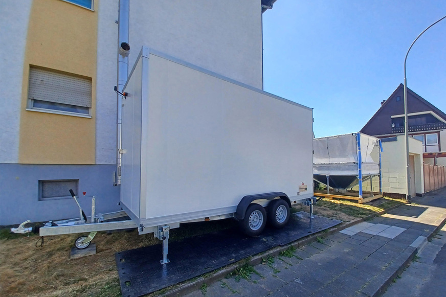 135 kW Pelletanlage mit Pelletlager vor dem zu versorgenden Mehrfamilienhaus.