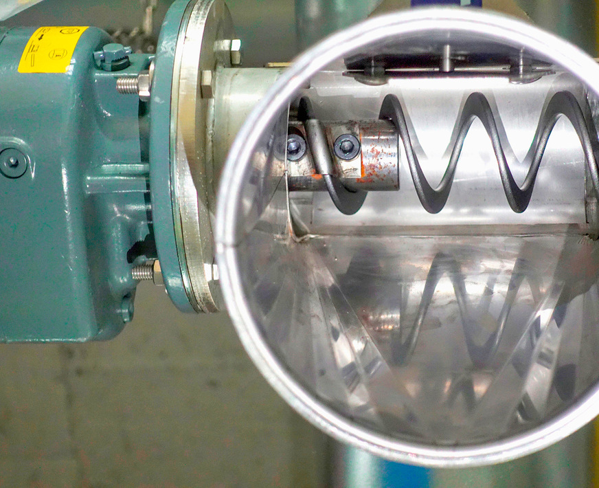 Drei Förderspiralen transportieren die Holzpellets über zwei Umlenkschächte zum Kessel. Jede Spirale endet mit Antriebsmotor und Abwurfschacht. Den Anfang des Fördersystems bildet eine Austragsschnecke mit Rührwerk am Speicherboden.