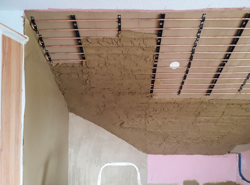 Mit der ersten Lehmputzlage wurde die Systemrohrebene in Nassbauweise&nbsp;ausgebildet. Dabei war darauf zu achten, eine optimale Haftung und vollkommene Einbettung des Systemrohres herzustellen.