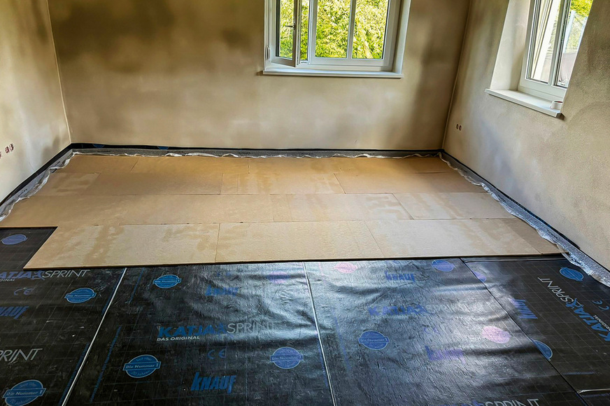 Zum Schutz vor aufsteigender Bodenfeuchtigkeit erfolgte die Verlegung einer Abdichtungsbahn inklusive Anschlussstreifen und wandseitiger Aufkantung. Anschließend wurde ein Randdämmstreifen angebracht und eine Holzfaserdämmplatte eingesetzt.