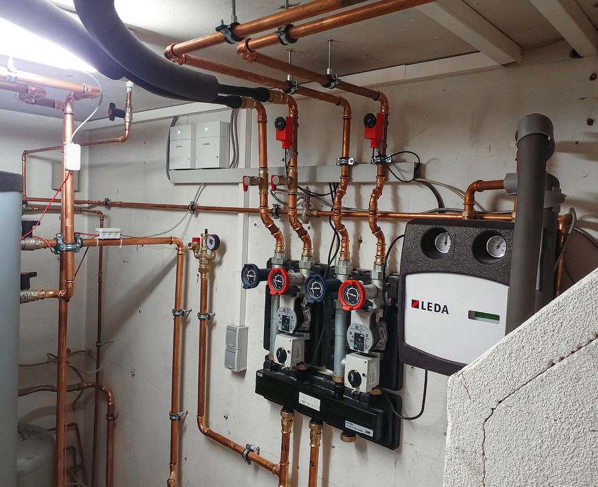 Die beiden Heizkreis-Pumpengruppen wurden auf einen Verteilerbalken montiert, rechts ist die Pumpengruppe mit Rücklauftemperaturanhebung und Steuerei﻿nheit des Kessel-Ladekreises des wassergeführten Kachelofeneinsatzes zu sehen.