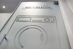 Die Kermi-Glastür als Abtrennung des Stauraums für Waschmaschine und Trockner wurde mit einem sandgestrahlten Dekor versehen. 