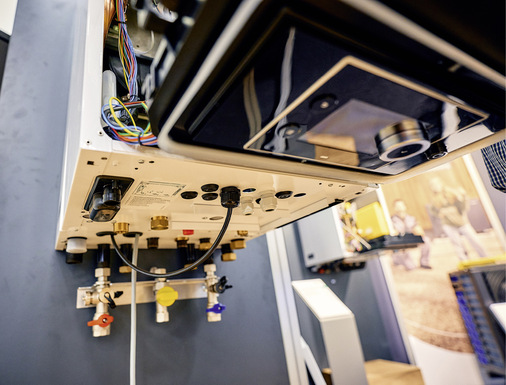  5 Der Kessel, das Kit 65 und die Außeneinheit werden im Folgenden hydraulisch miteinander verbunden. Hierfür wird die Vorderwand des eingehängten Gas-Brennwertkessels entfernt und das Kesselschaltfeld heruntergeklappt. An den Vor- und Rücklaufanschlüssen des Kessels werden die mitgelieferten Leitungen samt Dichtungen montiert. Der Lieferumfang enthält die Leitungen für die Installation am Gasanschluss sowie die U-Rohrleitungen mit Dämmung für den Vor- und Rücklauf der Wärmepumpe. Der Anschluss der Wärmepumpe kann rechts- oder linksseitig erfolgen. Der Hersteller empfiehlt den Einbau zweier optionaler Absperrhähne für den Vor- und Rücklauf der Wärmepumpe. Diese bleiben für den Zeitraum des Gas-Solobetriebes geschlossen.