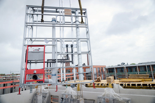 Mithilfe des Krans wurden die industriell vorgefertigten Installationswände von Tecesystem als Paket mit den entsprechenden Abladehilfen auf das Stockwerk gehoben. - © Frank Peterschröder
