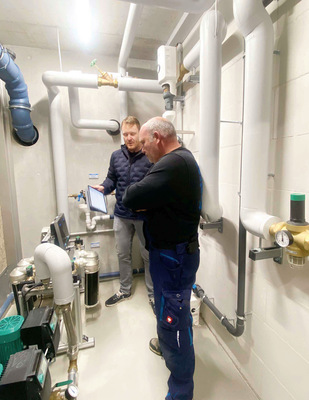 Matthias Laber (hinten), Gebietsleiter bei Perma-Trade, weist ­Heiko Gärtner (vorne) vom SHK-Betrieb Sanitär Kratzer GmbH in die ­Funktionsweise der App ein, mit der sich die Kalkschutzgeräte ­einfach und übersichtlich überwachen lassen.