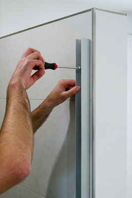 Mit einem Schraubendreher wird das Wandanschlussprofil anschließend fest fixiert. Dann kann die restliche Montage der Dusche erfolgen.