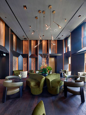 Warme Grüntöne, samtige Textilien und skulpturale Leuchten prägen das Interior Design von Landau + Kindelbacher. Die harmonische Kombination aus dunklem Holz, goldschimmernden Wandpaneelen und sorgfältig platzierten Akzenten schafft eine einladende Atmosphäre mit besonderer Tiefe.