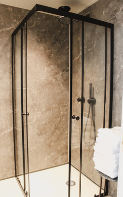 Ixmo-Armaturen verleihen der Dusche ein elegantes, minimalistisches Design. In Schwarzchrom strahlen sie besondere Exklusivität aus. Kopf- und Handbrause sorgen für ein erstklassiges Duscherlebnis für die Gäste.