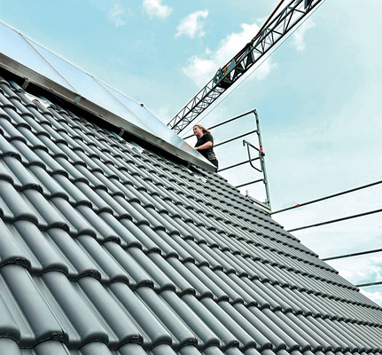 Jana Sonntag kontrolliert auf dem Dach eine neu installierte thermische ­Solaranlage.