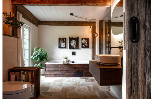 Eingebettet in eine vom Künstler maßgefertigte Verkleidung aus alten Eichenbalken wird die Badewanne zum optischen Blickfang .