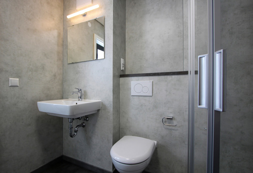 Seriell vorgefertigte Badmodule werden zur Baustelle geliefert, vor Ort aufgestellt und mit den zuvor vorbereiteten Schnittstellen verbunden. Nach der Überprüfung auf Funktion und Dichtigkeit der Leitungen werden die vollflächigen Easi-Bath-Wandverkleidungen angebracht.