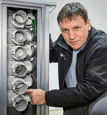 Lüftungsspezialist Reiner Hackl demonstriert, wie Sensoren im RAV-Verteiler Feuchte und CO₂ messen und die Klappen für die ­benötigte Frischluft steuern.