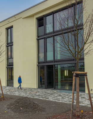 Südfassade mit Vorplatz der Carderie in Wangen/Allgäu, einem ­Industriegebäude Baujahr 1913 nach Umbau und Erweiterung. Unter dem Pflasterbelag sitzt der ­Regenspeicher, bestehend aus fünf Behältern und einem Filterschacht, jeweils durch Abdeckungen der Klasse D 400 für Lkw und Feuerwehr befahrbar.