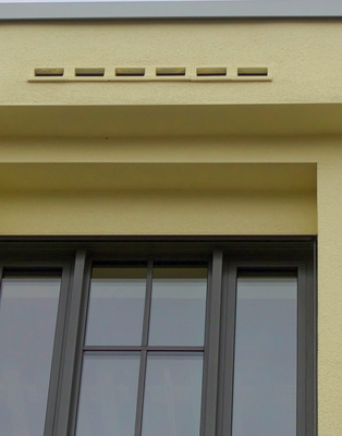Einflugschlitze für Fledermäuse in der Attika des Dachvorsprungs. Die Fledermauskästen ­wurden im Zuge der Gebäudemodernisierung in die denkmalgeschützte Fassade integriert.