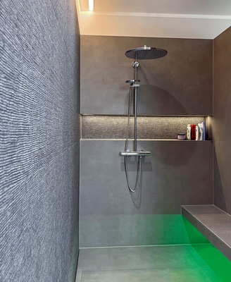 Die Wellenstruktur schafft Aufmerksamkeit. Das Dekor wird in die ­angrenzende duschbreite Shampoonische hineingezogen und durch eine durchgängige LED-Line illuminiert.